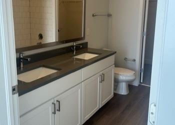 Farmhouse sinks, white cabinets, and grey quartz counter tops in select units